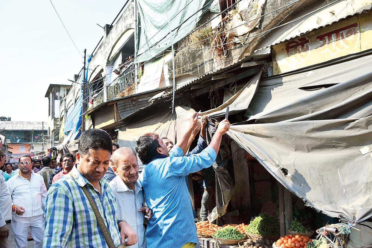 Tarpaulins being removed from a shop at Bidhan Market in Siliguri on Tuesday. 