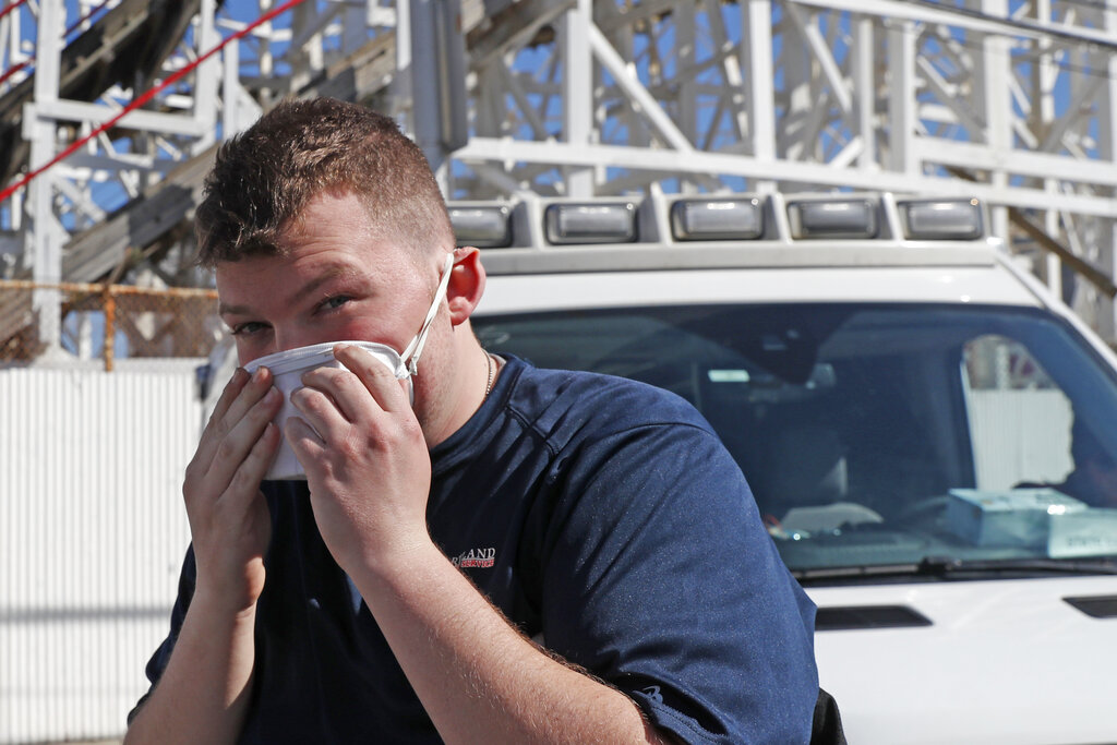 Evan Demaree, a Heartland Disaster Response Team ambulance attendant from Lafayette, Ind., dons his face mask before taking a stroll on the boardwalk at Coney Island, Thursday, April 2, 2020, while awaiting a call to duty in the Brooklyn borough of New York.
