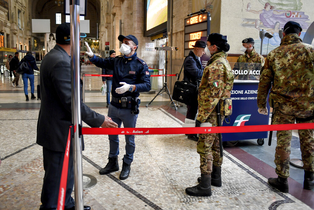 Police officers and soldiers check passengers leaving from Milan main train station, Italy, Monday, March 9, 2020.