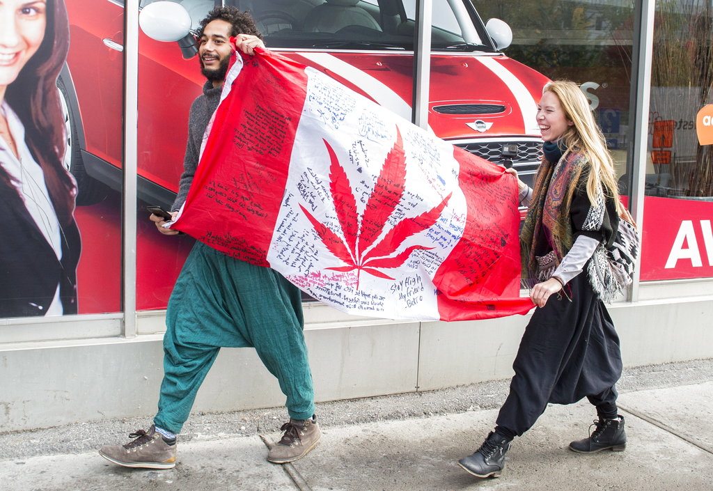 People hold up a Canadian flag with a marijuana logo on it outside a government cannabis store in Montreal on Wednesday.