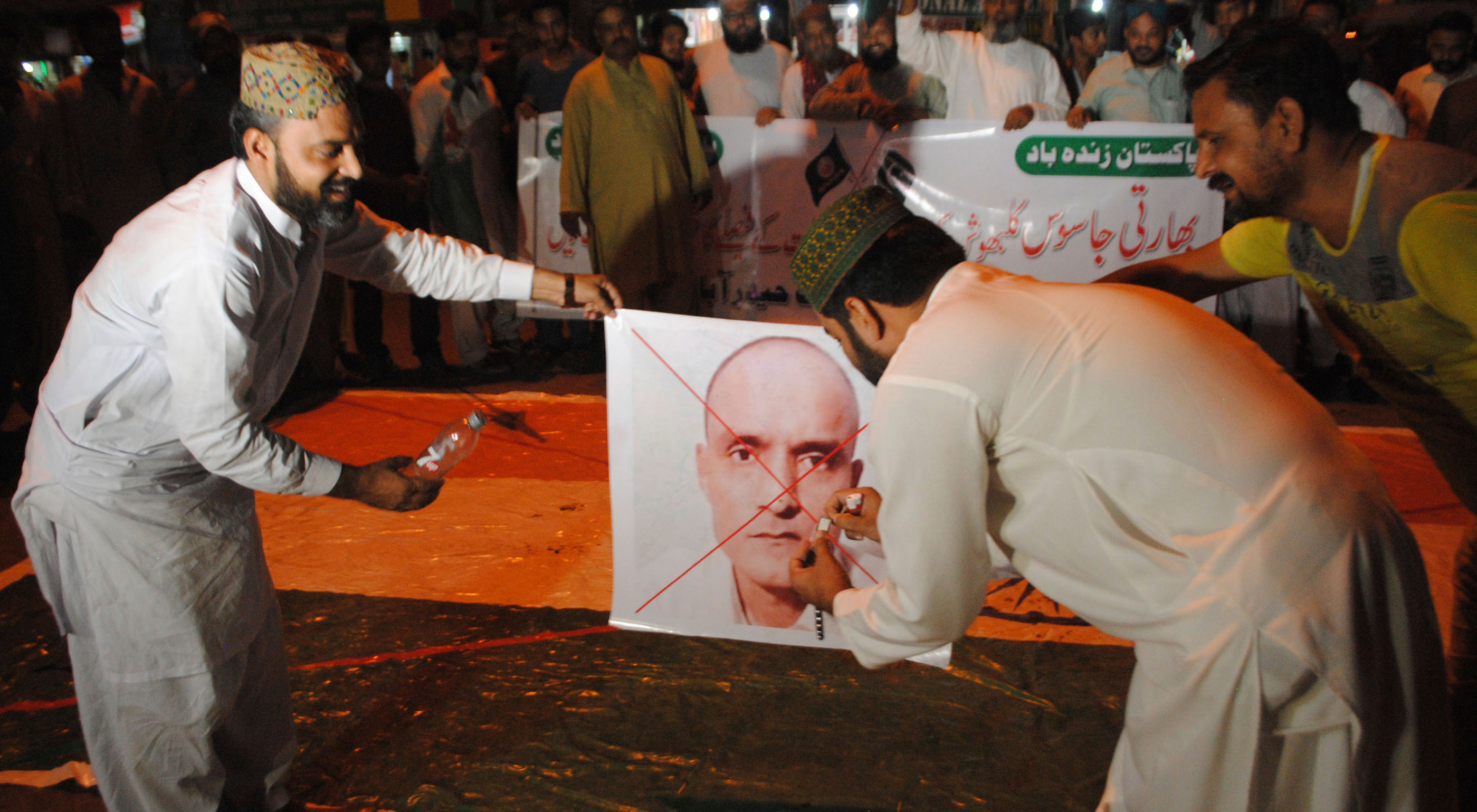 Pakistani protesters prepare to burn a poster of Kulbhushan Jadhav in Hyderabad, Pakistan, on July 17, 2019. India has maintained that Jadhav was kidnapped from Iran; Pakistan argues that Jadhav was arrested in Balochistan, near the border with Iran, after entering Pakistani territory illegally. 
