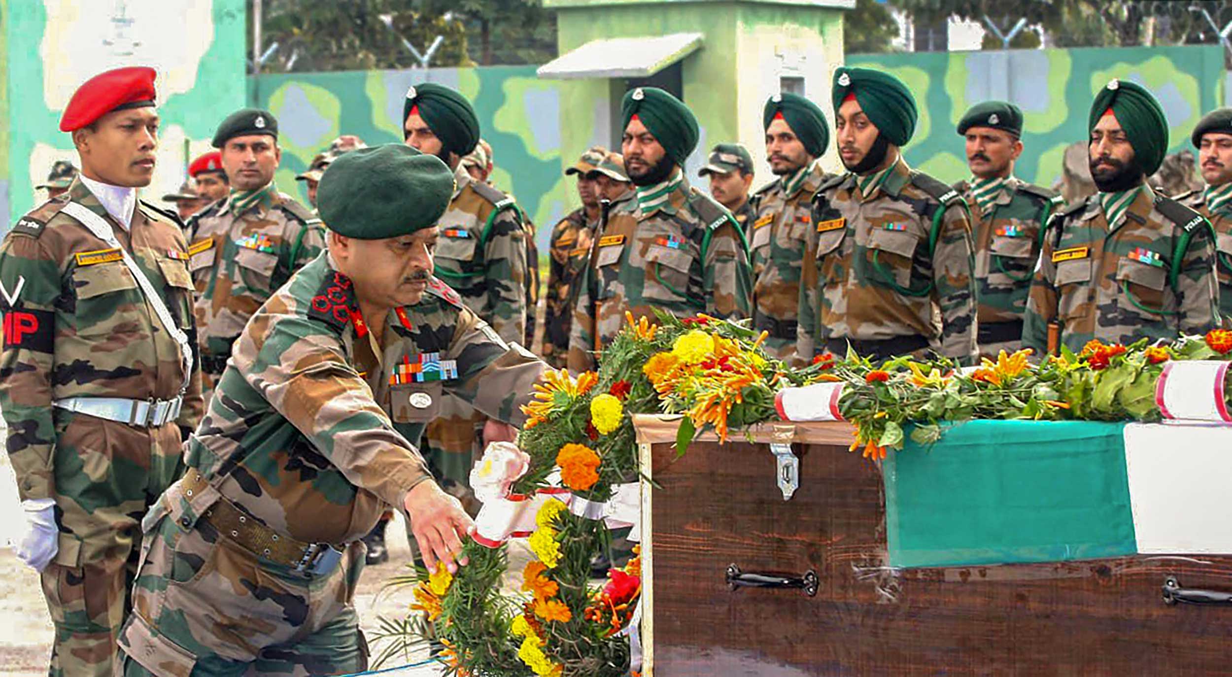 An army official lays a wreath on the remains of Major Chitresh Bisht, in Rajouri, on Sunday. 