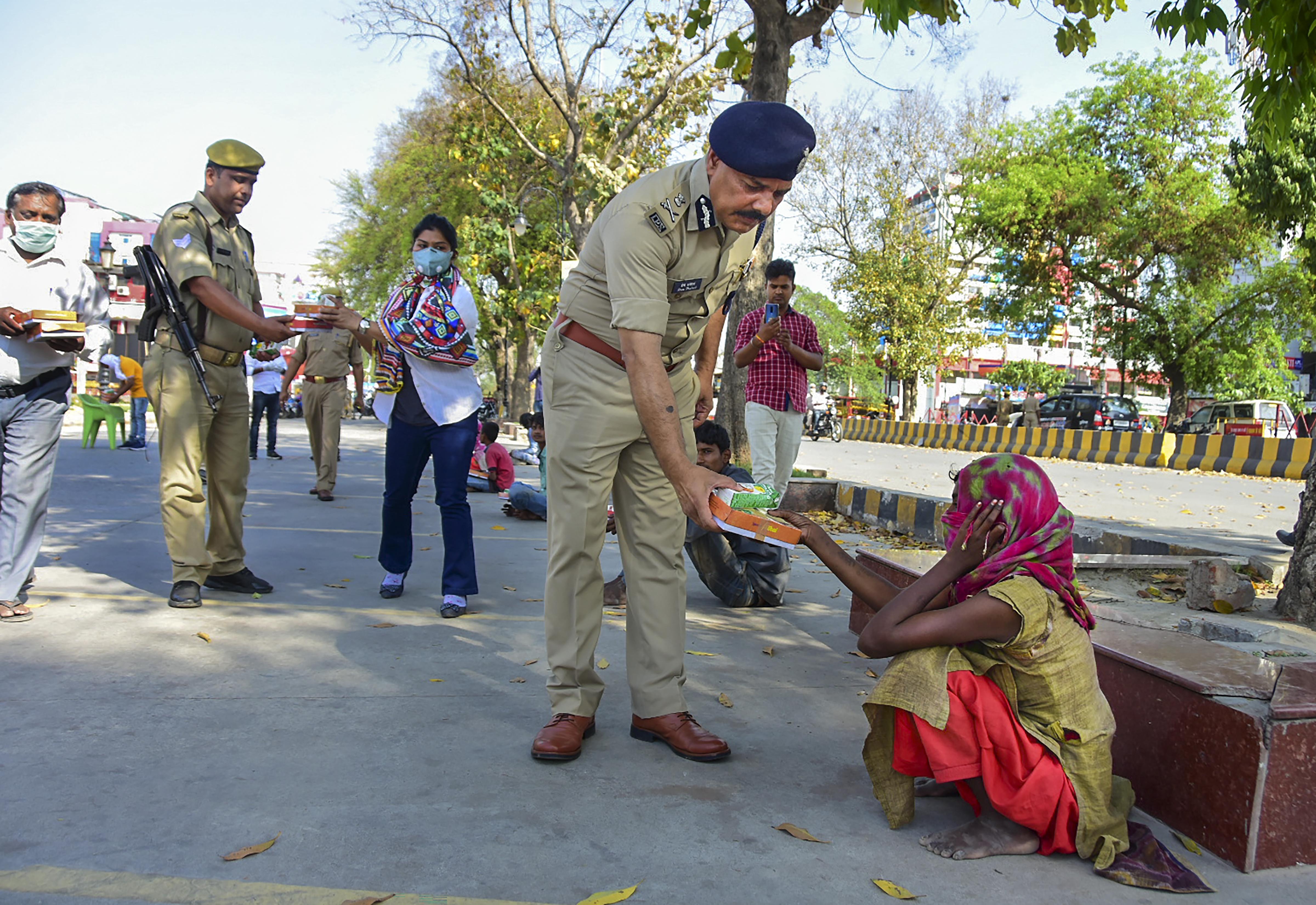 ADG Prem Prakash and other police personnel distribute food to homeless people during a 21-day nationwide lockdown in the wake of coronavirus pandemic, in Prayagraj, Wednesday, March 25, 2020