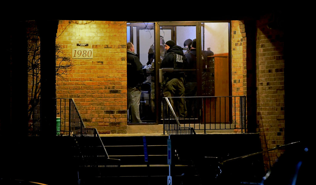 Investigators enter an apartment building in Aurora, where the gunman is believed to have lived.