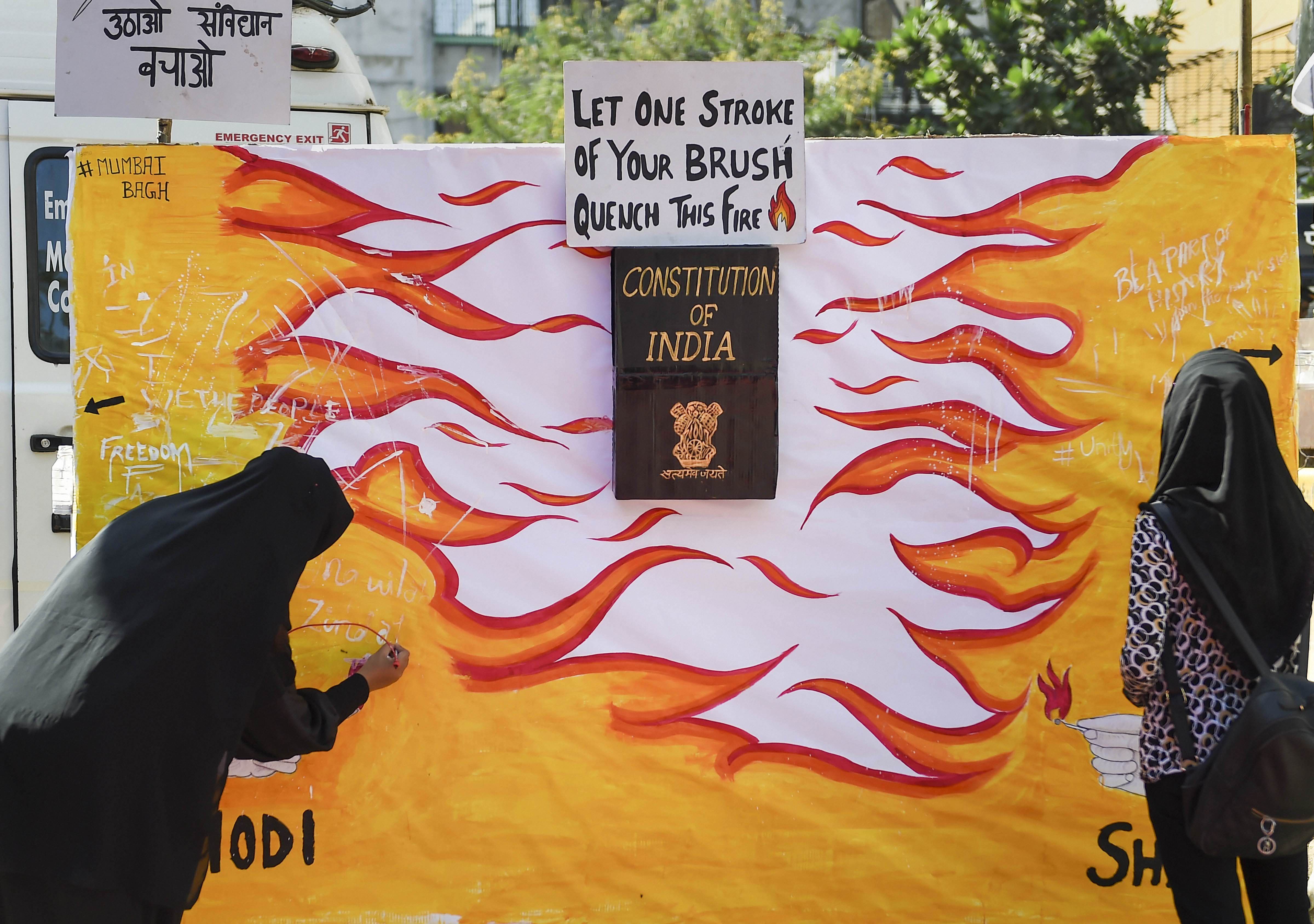 Protesters write on a wall during an anti-Citizenship Amendment Act (CAA) demonstration, in Mumbai on Thursday