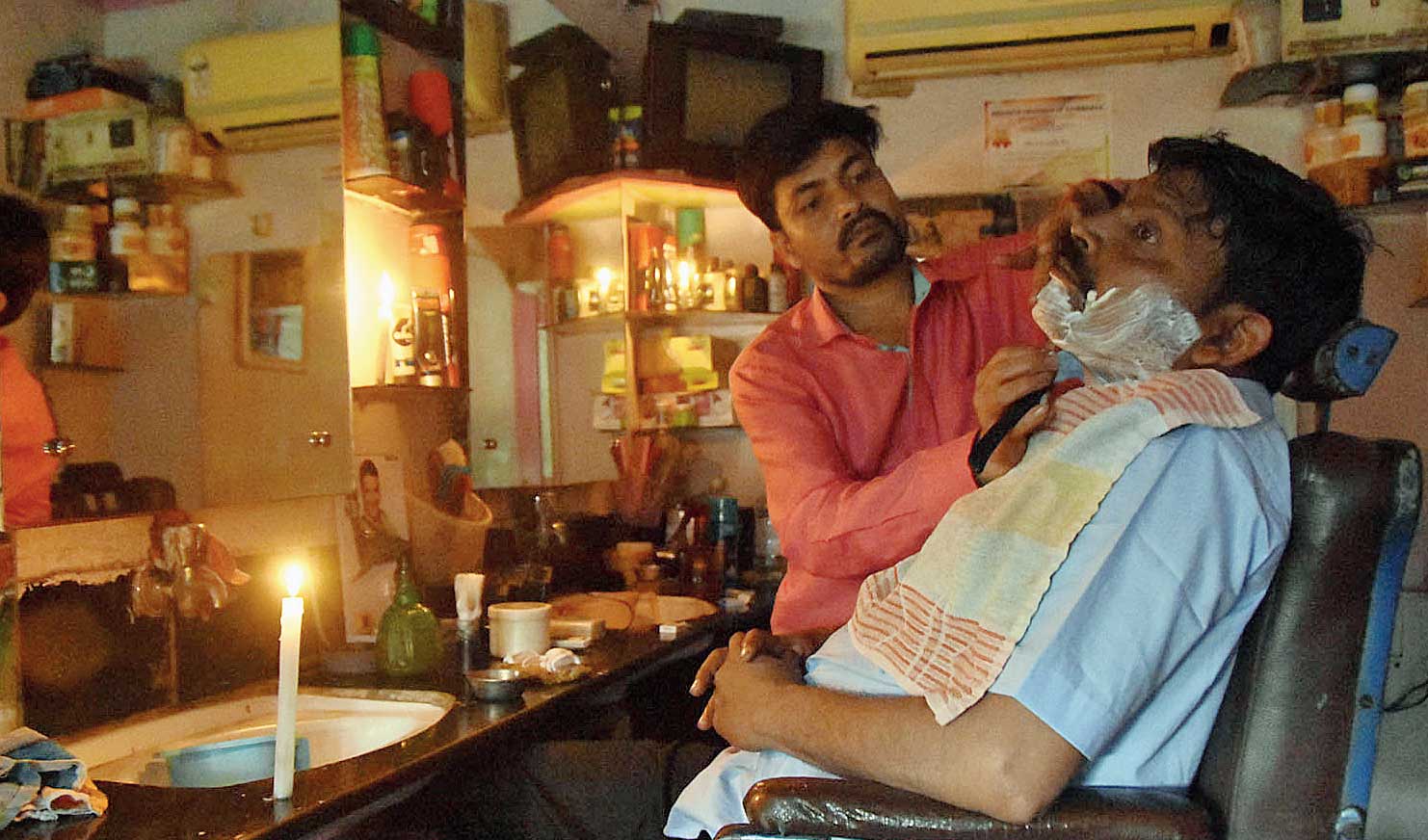 A barber attends to his customer by candlelight in Dhanbad on Wednesday. 
