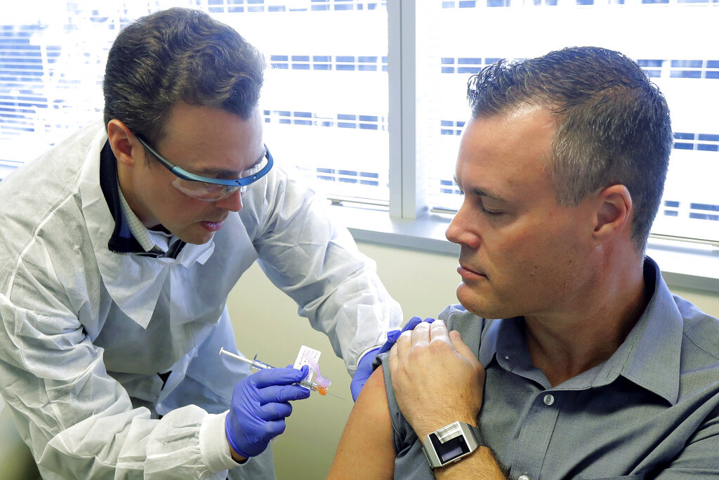 Pharmacist Michael Witte, left, gives Neal Browning a shot in the first-stage study of a potential coronavirus vaccine Monday, March 16, 2020, at the Kaiser Permanente Washington Health Research Institute in Seattle.