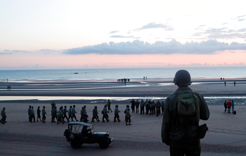 A World War II re-enactor looks out over Omaha Beach, in Normandy, France, at dawn on Thursday, June 6, 2019 during commemorations of the 75th anniversary of D-Day.