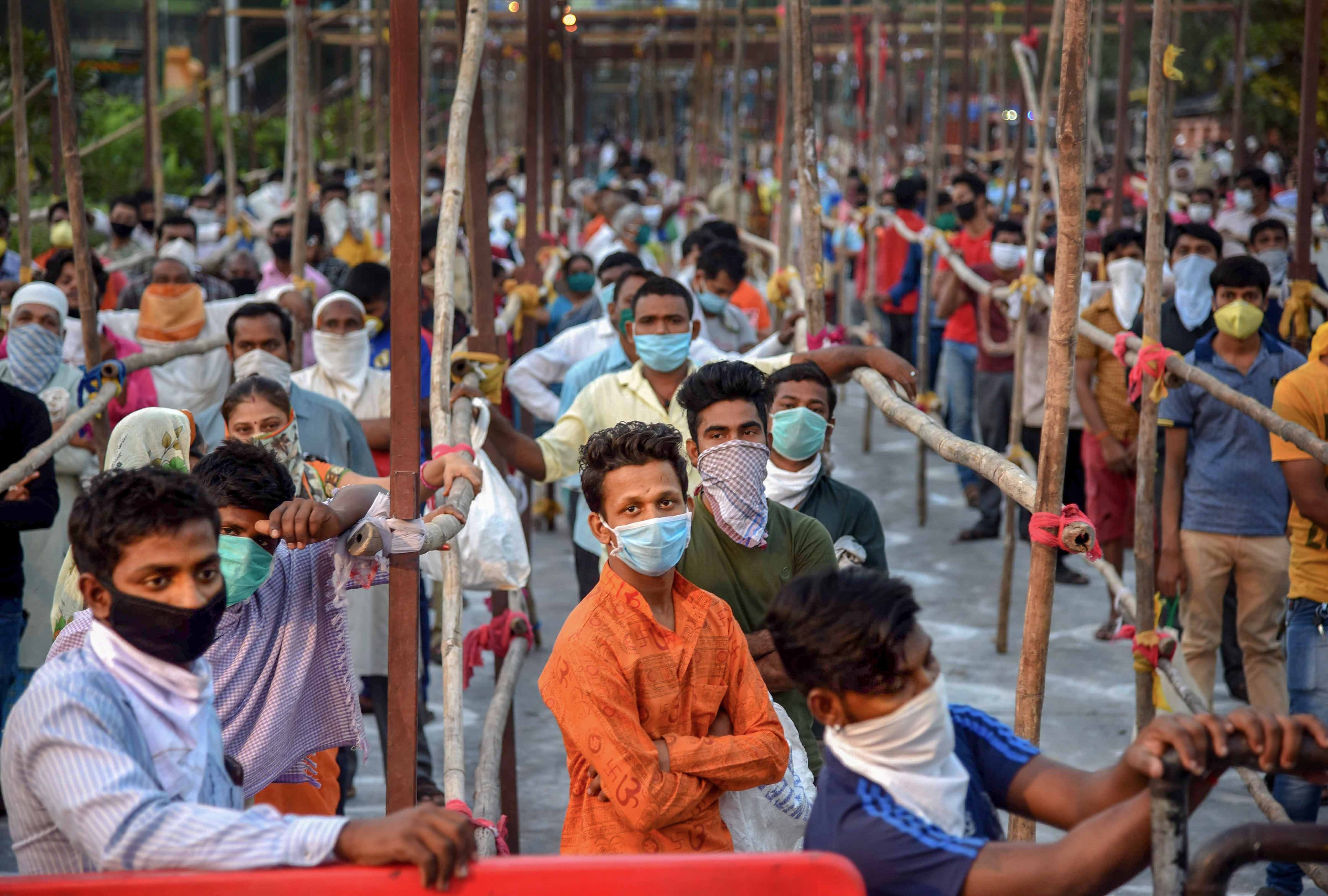 People stand in queues to enter APMC Vegetable Market, during a nationwide lockdown, imposed in the wake of coronavirus pandemic in Navi Mumbai, Monday, March 30, 2020