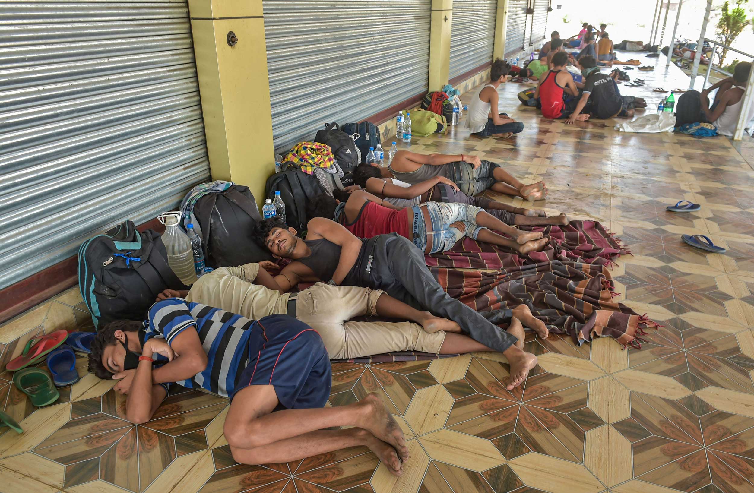 Migrant workers rest near closed shops along the Mumbai-Nashik highway in Thane on Friday.
