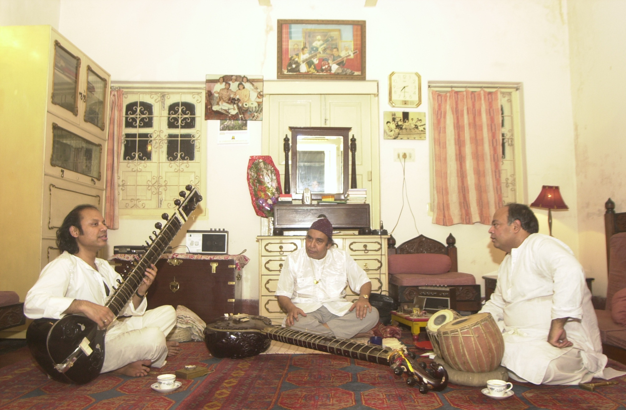 Nishat Khan (left) plays the sitar for his father Imrat Khan (centre) at their home in Kolkata.