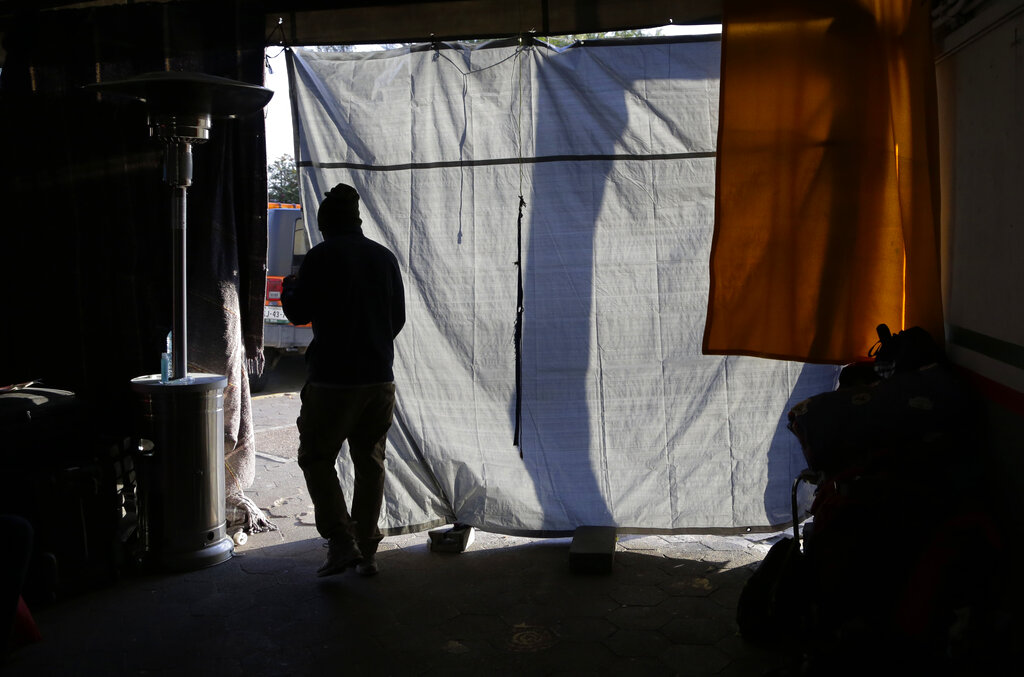 An immigrant passes through a makeshift doorway in the encampment for asylum seekers waiting to cross the nearby US-Mexico bridge, in Matamoros, Mexico. The latest proposal President Donald Trump and Senate Republicans made to fund the wall includes provisions that would be far more consequential than the wall, by making the already difficult task of winning asylum even harder.