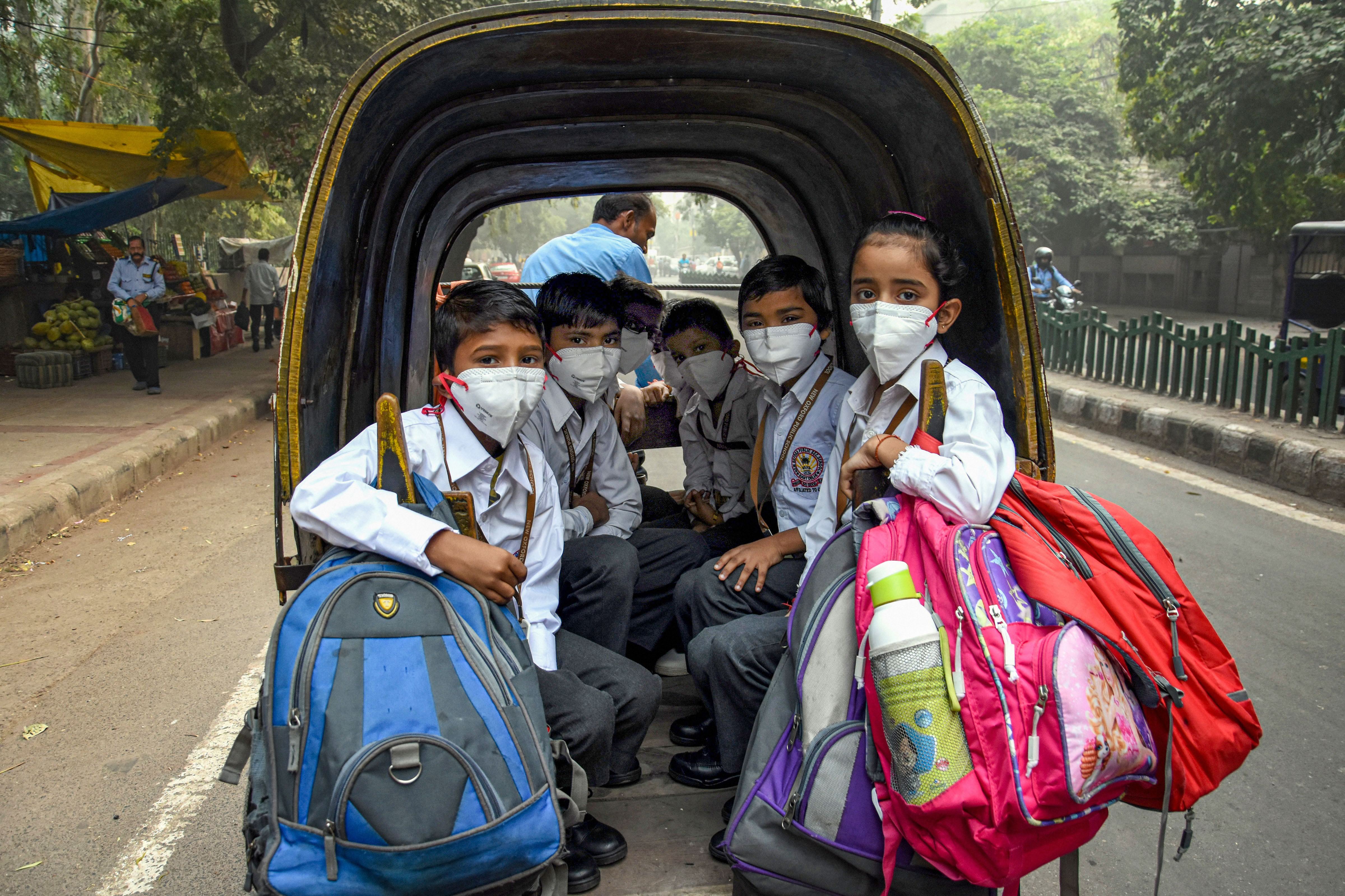 Students, wearing masks to get protection from air-pollution, go to school in a rickshaw, in New Delhi, Friday, November 1, 2019. 