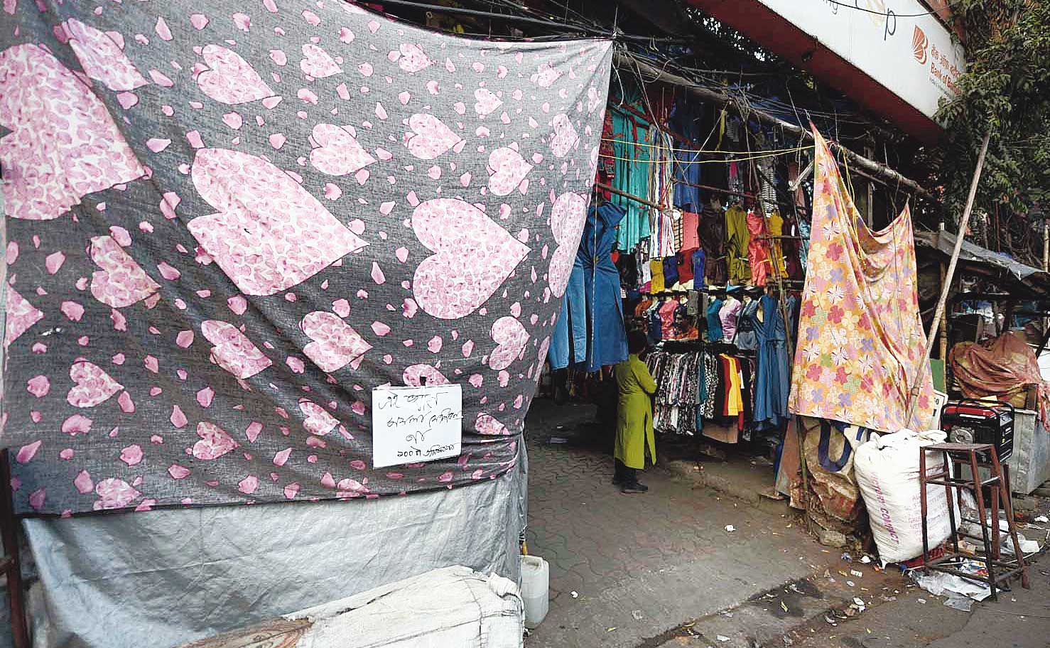 Two stalls on a pavement in Gariahat with bed sheets tied to hooks that used to hold plastic or tarpaulin screens until Wednesday. The piece 
of paper clipped to the first bed sheet states in Bengali that littering will invite a penalty of Rs 100. 