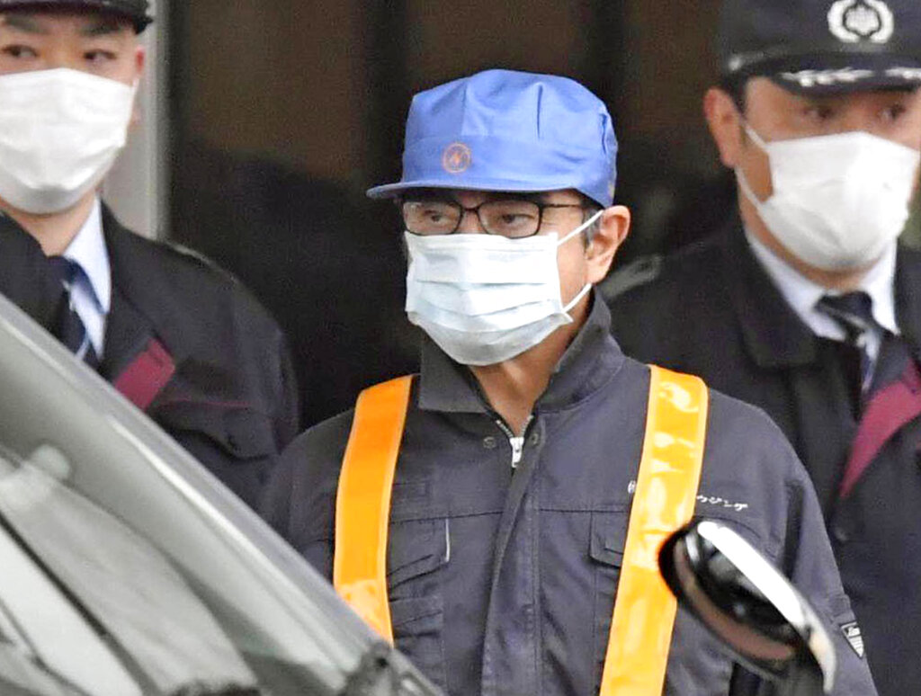 Carlos Ghosn, wearing a surgical mask and a blue cap, leaves the Tokyo Detention Centre on Wednesday.