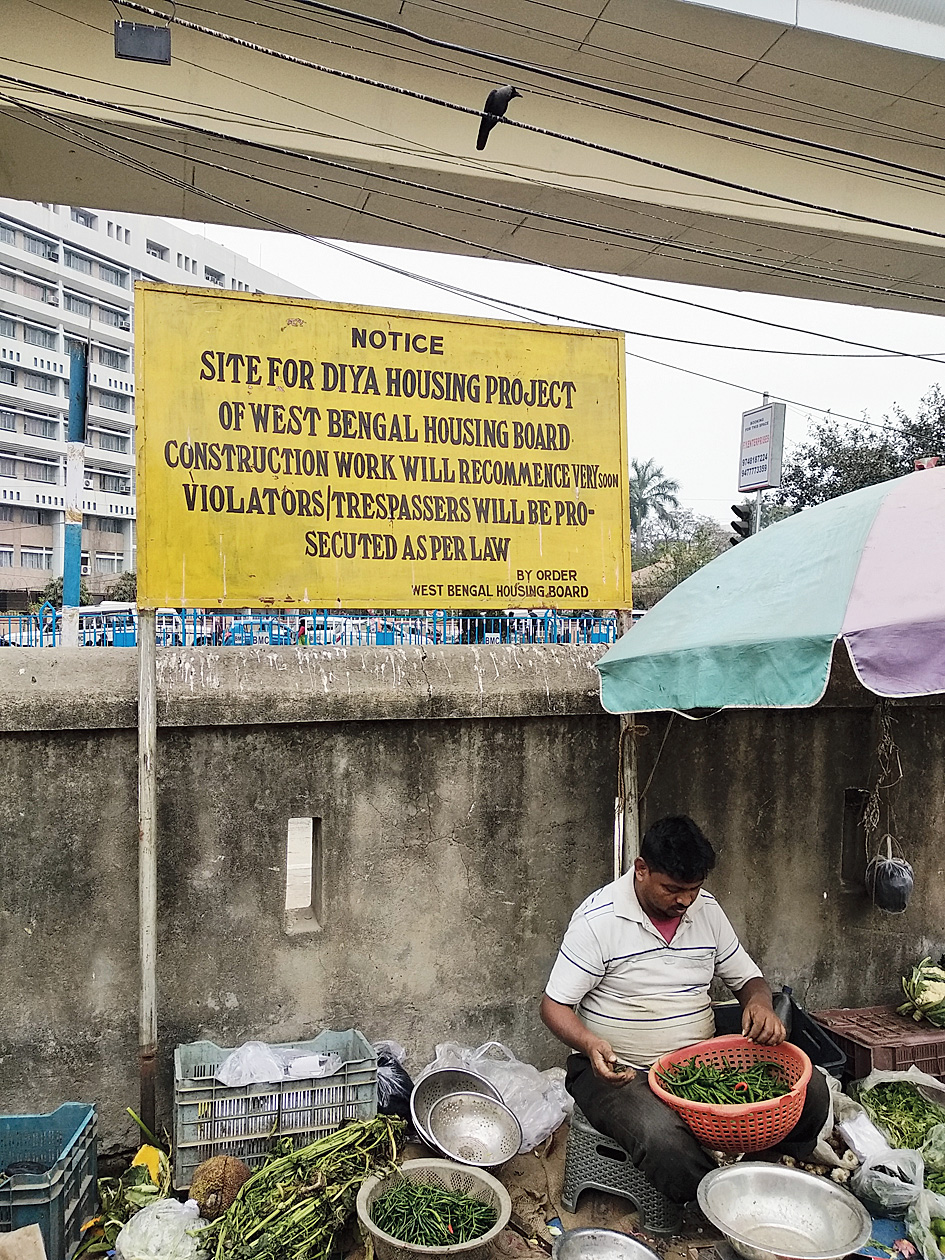 A hawker does business under a housing board notice saying tresspassers would be prosecuted.