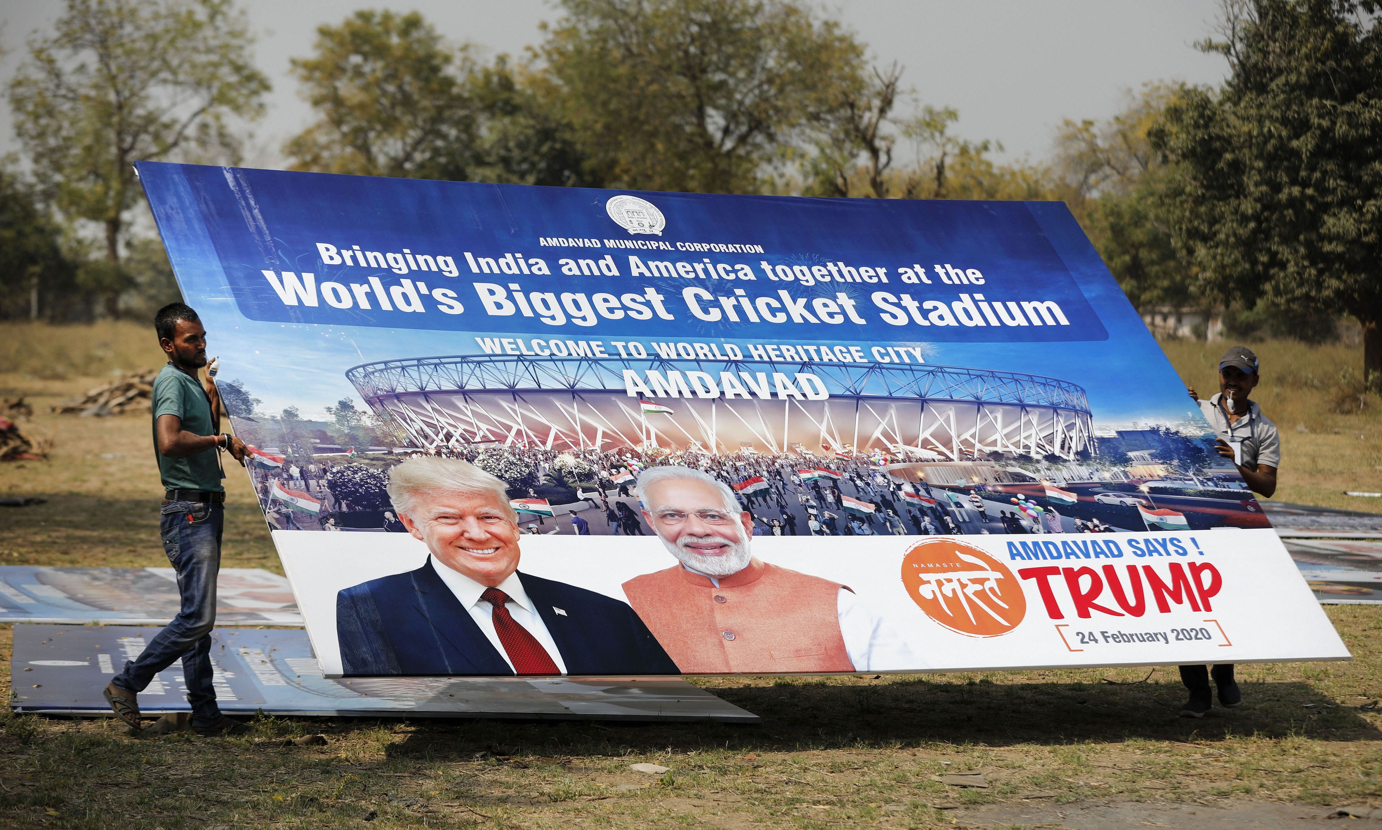 Workers carry a hoarding with pictures of Prime Minister Narendra Modi and US President Donald Trump as preparations are underway for the 'Namaste Trump' event, in Ahmedabad, Wednesday, February 19, 2020
