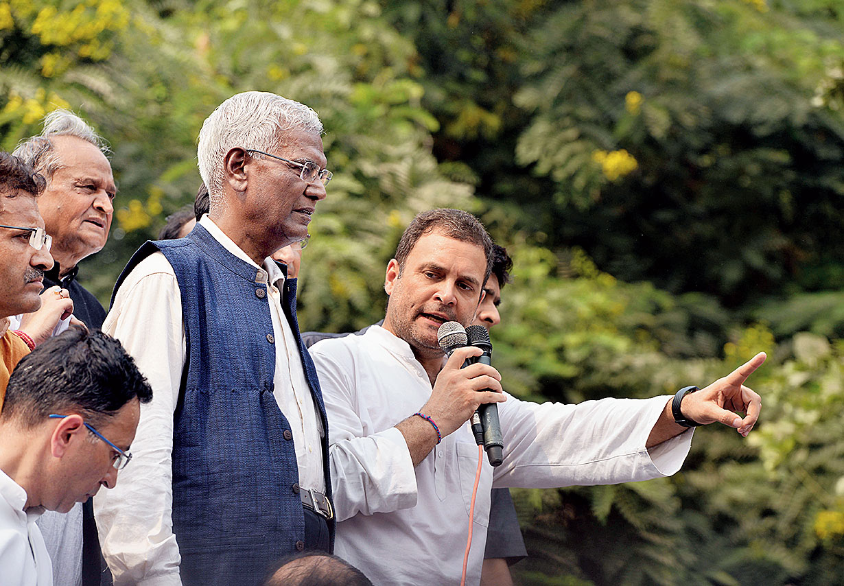 Rahul addresses the crowd, standing atop a truck, with D. Raja by his side.