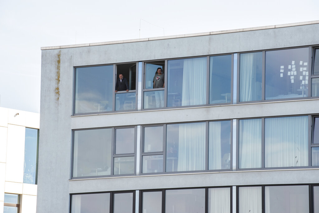 In this photo provided by the Alfred-Wegener-Institut and taken on May 6, 2020, MOSAiC participants stand at the window of their rooms in the hotel, where they are in quarantined before returning to the MOSAiC expedition, in Bremerhaven, Germany. They prepared for icy cold and trained to watch for polar bears, but a pandemic just wasn't part of the program. Now dozens of scientists are sitting in quarantine, waiting for permission to sail forth and capture a crucial moment in the polar calendar that's essential to their year-long Arctic research mission.