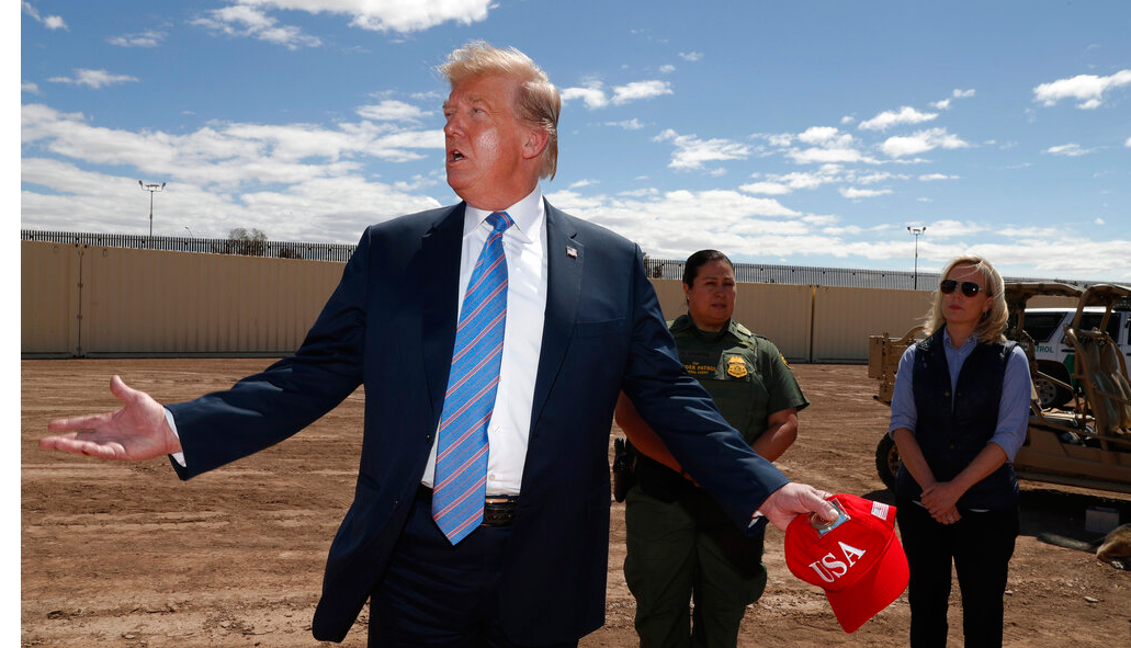President Donald Trump visits a new section of the border wall with Mexico in Calexico, California, Friday April 5, 2019. Gloria Chavez with the US Border Patrol, centre, and Homeland Security Secretary Kirstjen Nielsen listen.