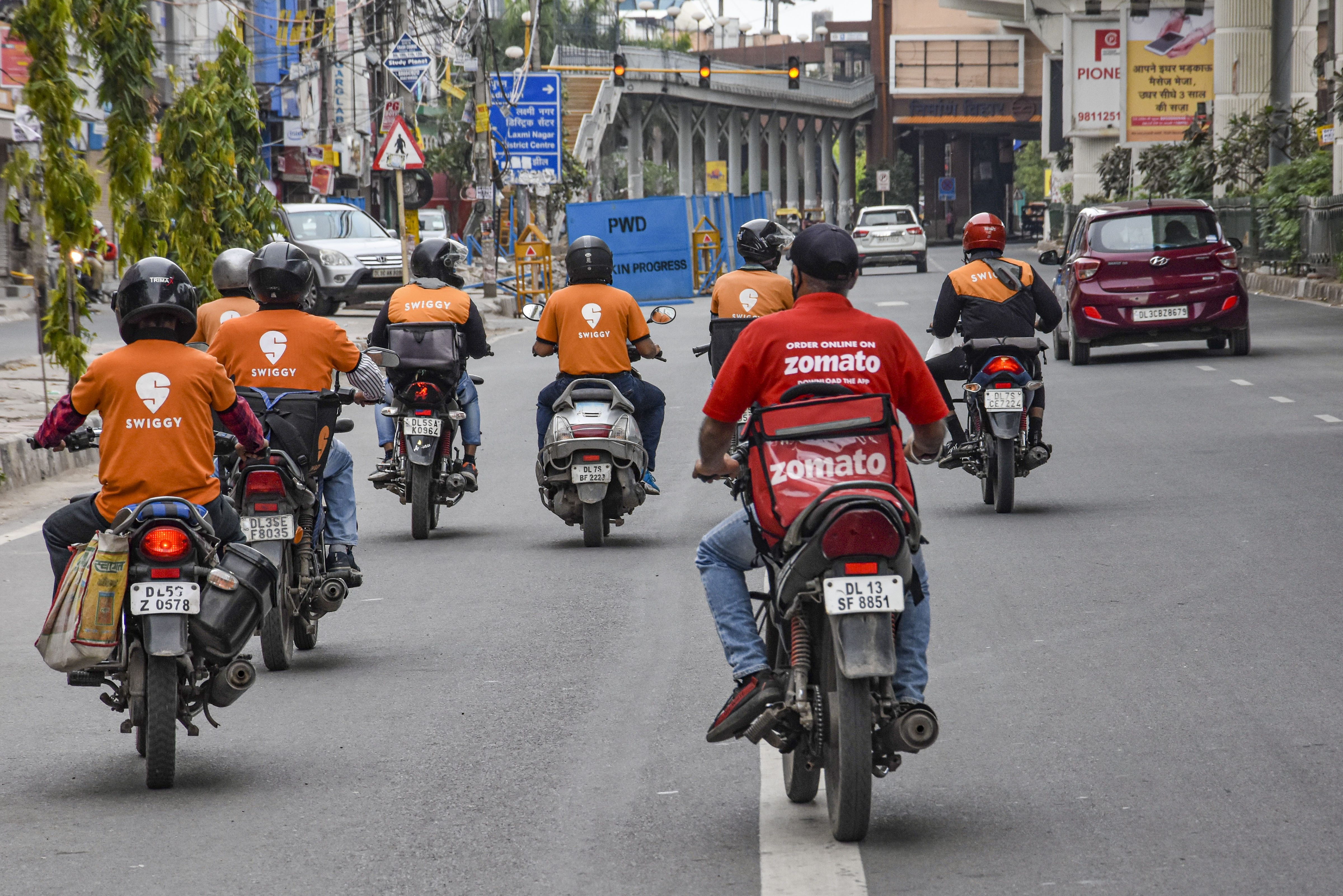 Deliverymen of food aggregators Swiggy and Zomato ride on their bikes towards their destinations during the nationwide lockdown, imposed in the wake of coronavirus pandemic, at Vikas Marg in East Delhi, Tuesday, March 31, 2020
