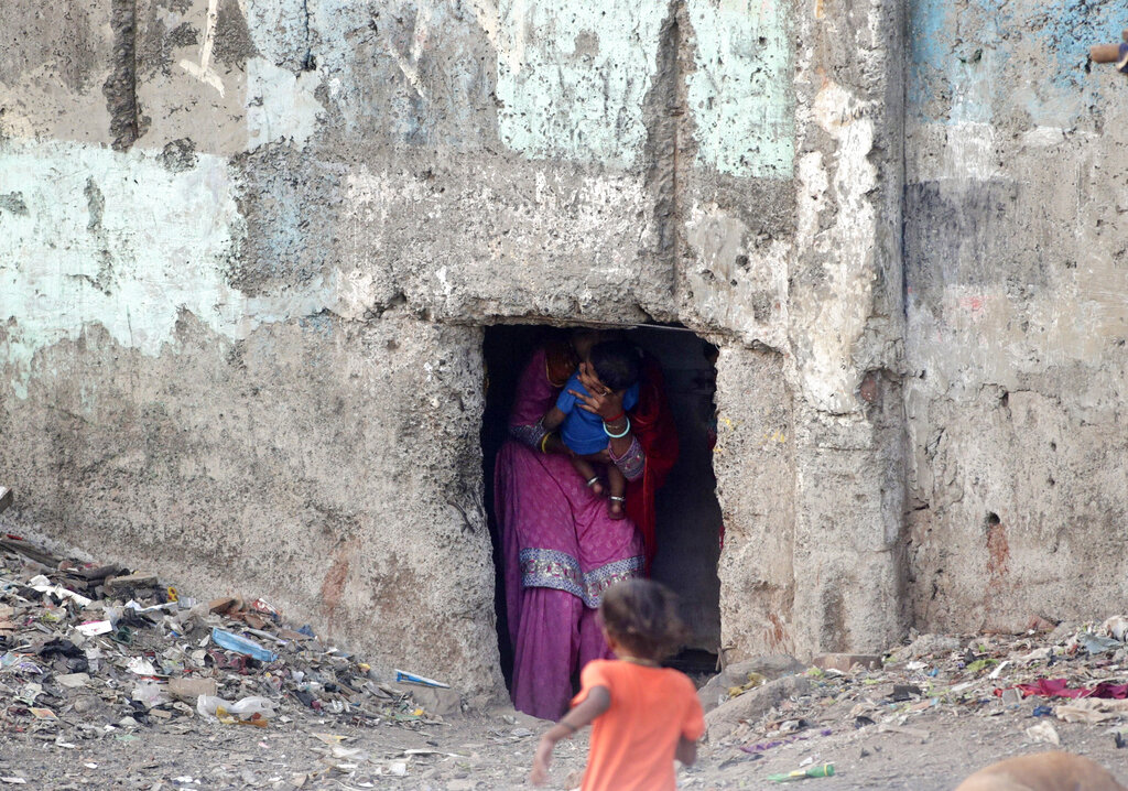 A woman holds a child and walks out from a narrow entry of a slum during lockdown to control the coronavirus pandemic in Mumbai, India, Saturday, April 11, 2020. Experts say that local spreading is inevitable in a country where tens of millions of people live in dense urban areas with irregular access to clean water, and that the exodus of the migrants will burden the already strained health system.