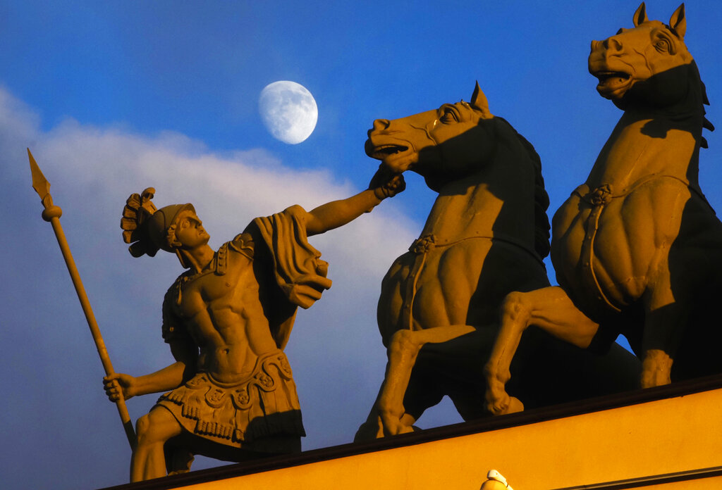The moon rises above a sculpture at Dvortsovaya (Palace) Square in St. Petersburg, Russia, Friday, March 6, 2020