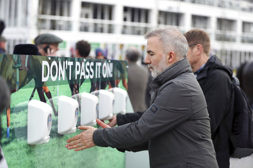 Racegoers use hand sanitiser to keep their hands clean on day one of the Cheltenham Horse Racing Festival at Cheltenham Racecourse, England, Tuesday March 10, 2020.