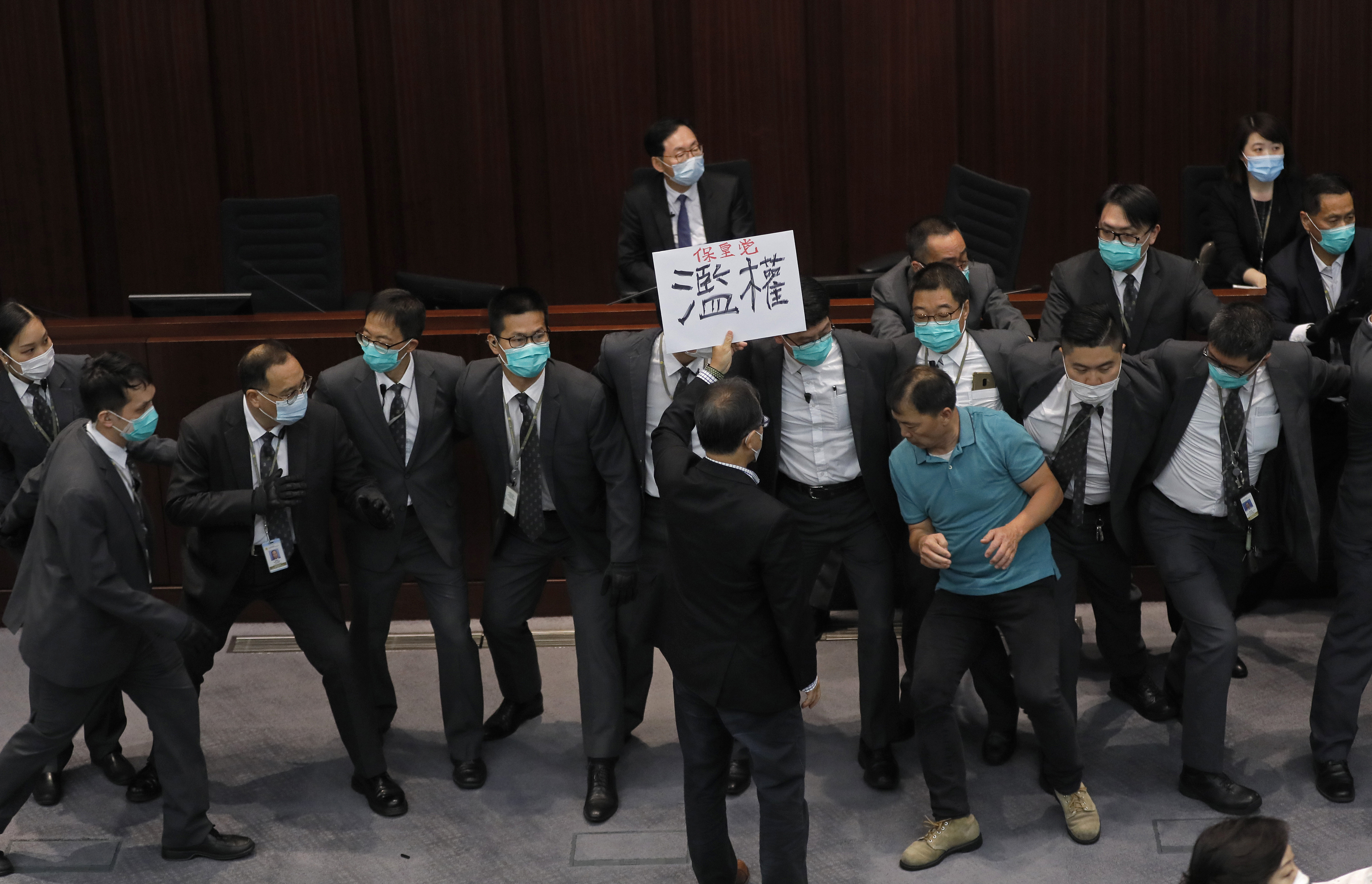 Pan-democratic legislator, Wu Chi-wai, right in green shirt, scuffles with security guards during a Legislative Council's House Committee meeting in Hong Kong