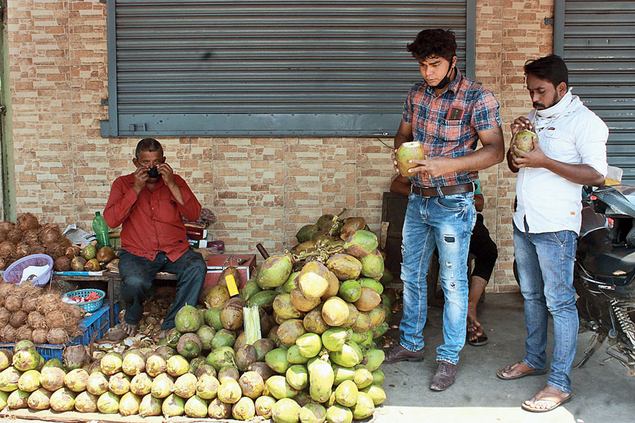 Customers enjoy coconut water on a hot sultry day at Sakchi in Jamshedpur on Sunday. 