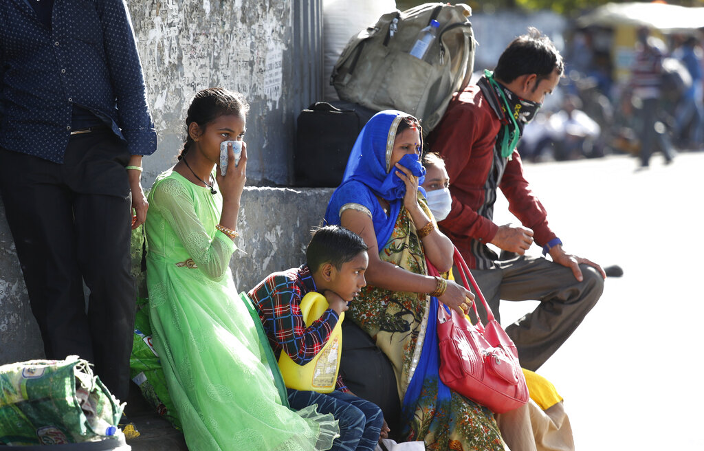 A migrant family wait for transportation to travel to their respective villages following a lockdown amid concern over spread of coronavirus in New Delhi, on Friday, March 27, 2020.