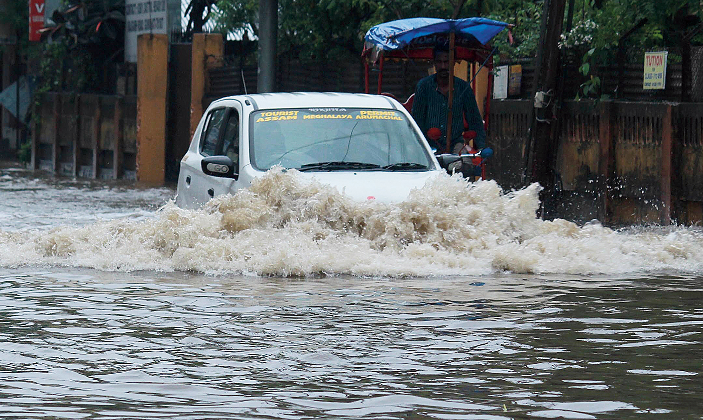 A car ploughs through waterlogged Rajgarh Road in Guwahati on Sunday.