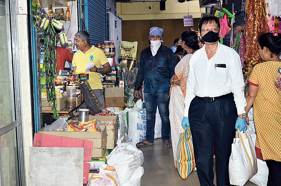 A customer wearing mask and gloves walks out of IA Market with bags full on Monday