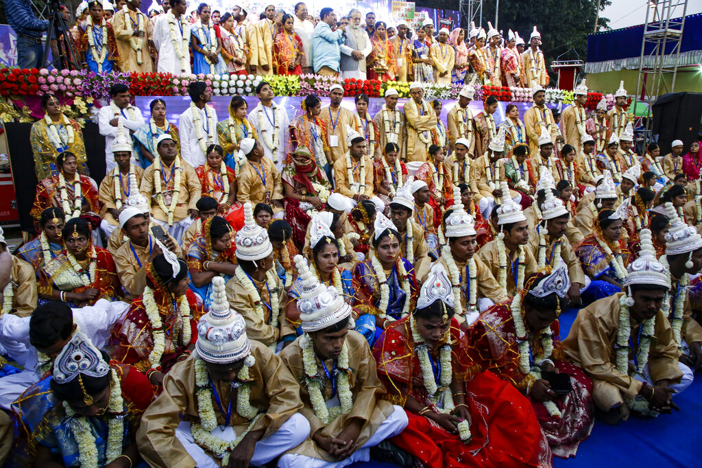 Brides and grooms sit for a group photograph during a mass marriage ceremony for eighty five couples of various religions in Kolkata
