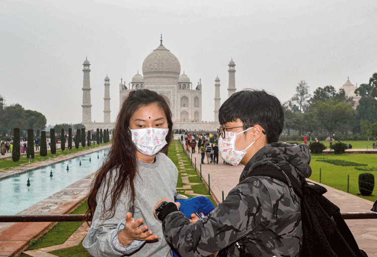 Tourists, wearing protective face masks, visit Taj Mahal in Agra on Tuesday. 