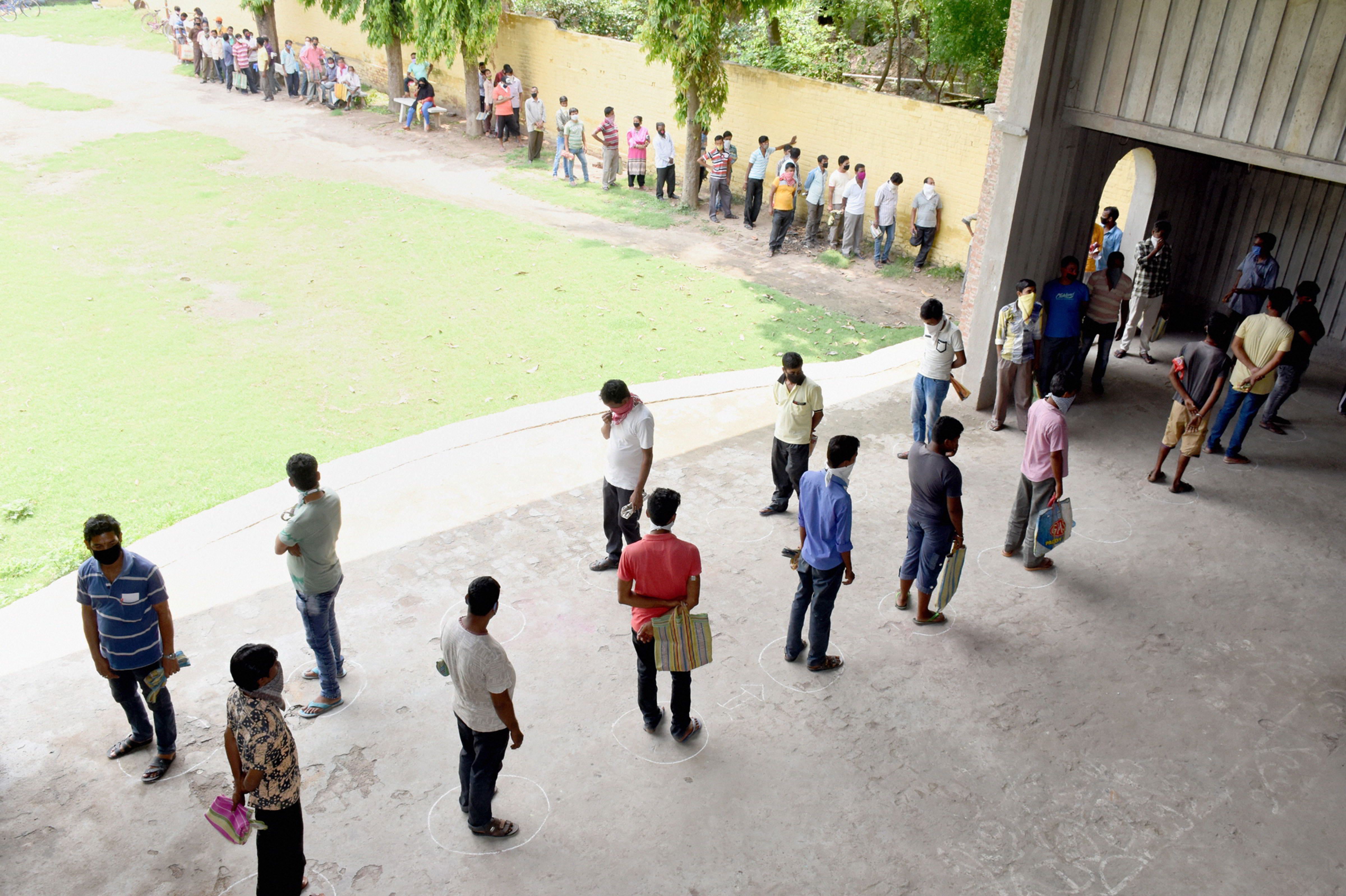 People practice social distancing as they stand in a queue to collect foods from NGO volunteers, during ongoing Covid-19 lockdown in Murshidabad district of West Bengal, Thursday, April 30, 2020