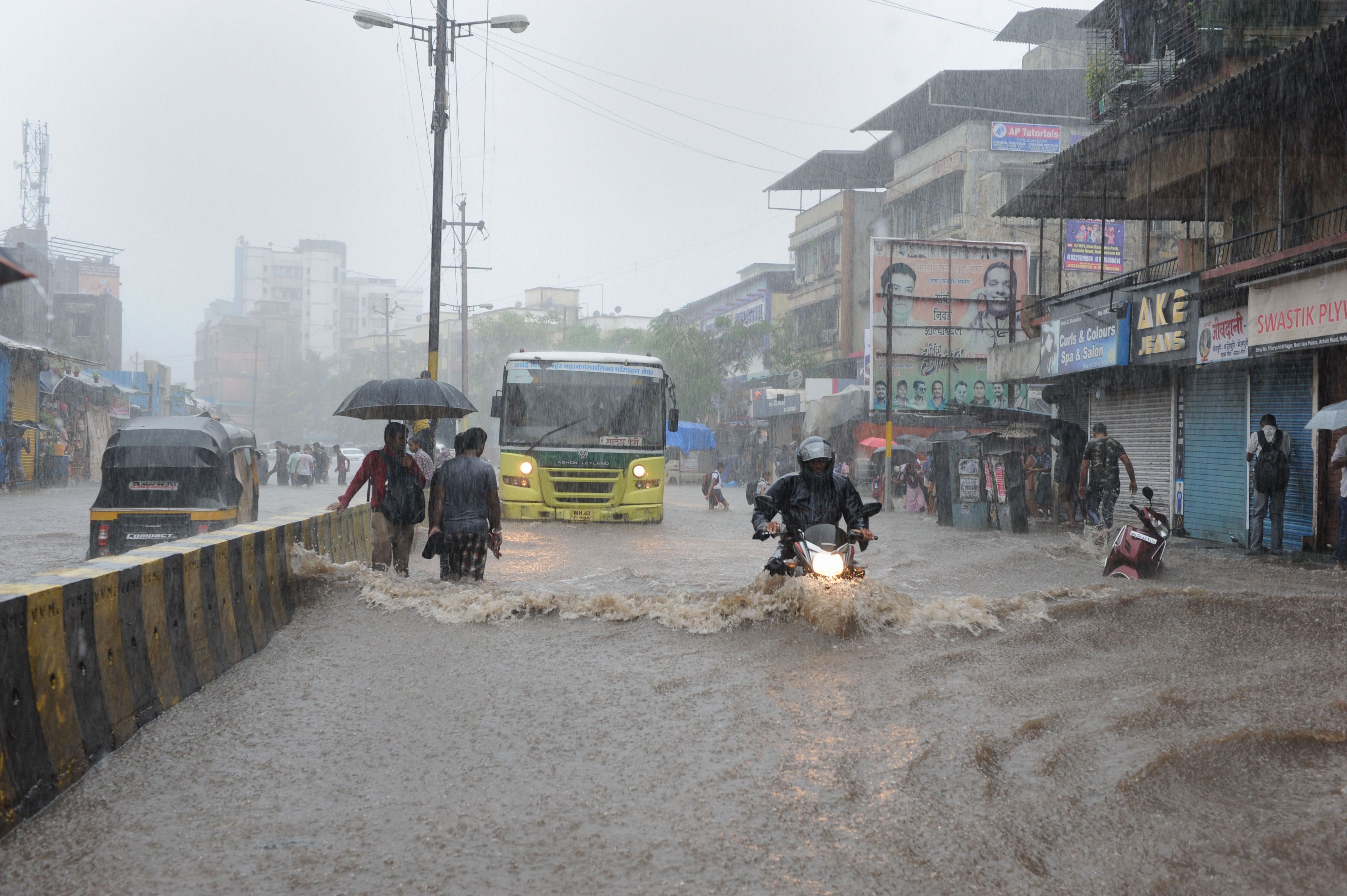 Commuters make their way through a waterlogged street in Nala Sopara town of Palghar district in Maharashtra on June 28.