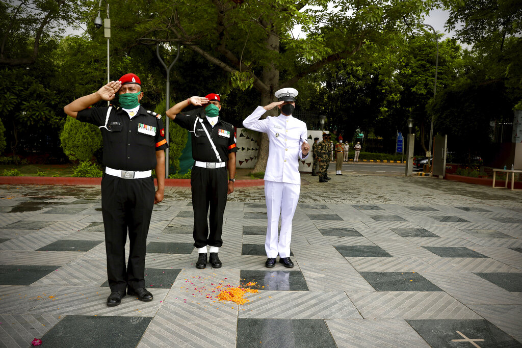 Indian armed forces personnel salute as an Indian Air Force helicopter showers flower petals at the National Police Memorial in New Delhi, India, Sunday, May 3, 2020.