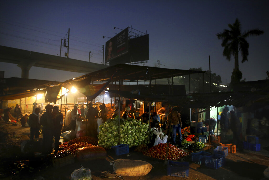 Indians buy vegetables early morning at a whole sale market in Lucknow, India, Monday, January 20, 2020