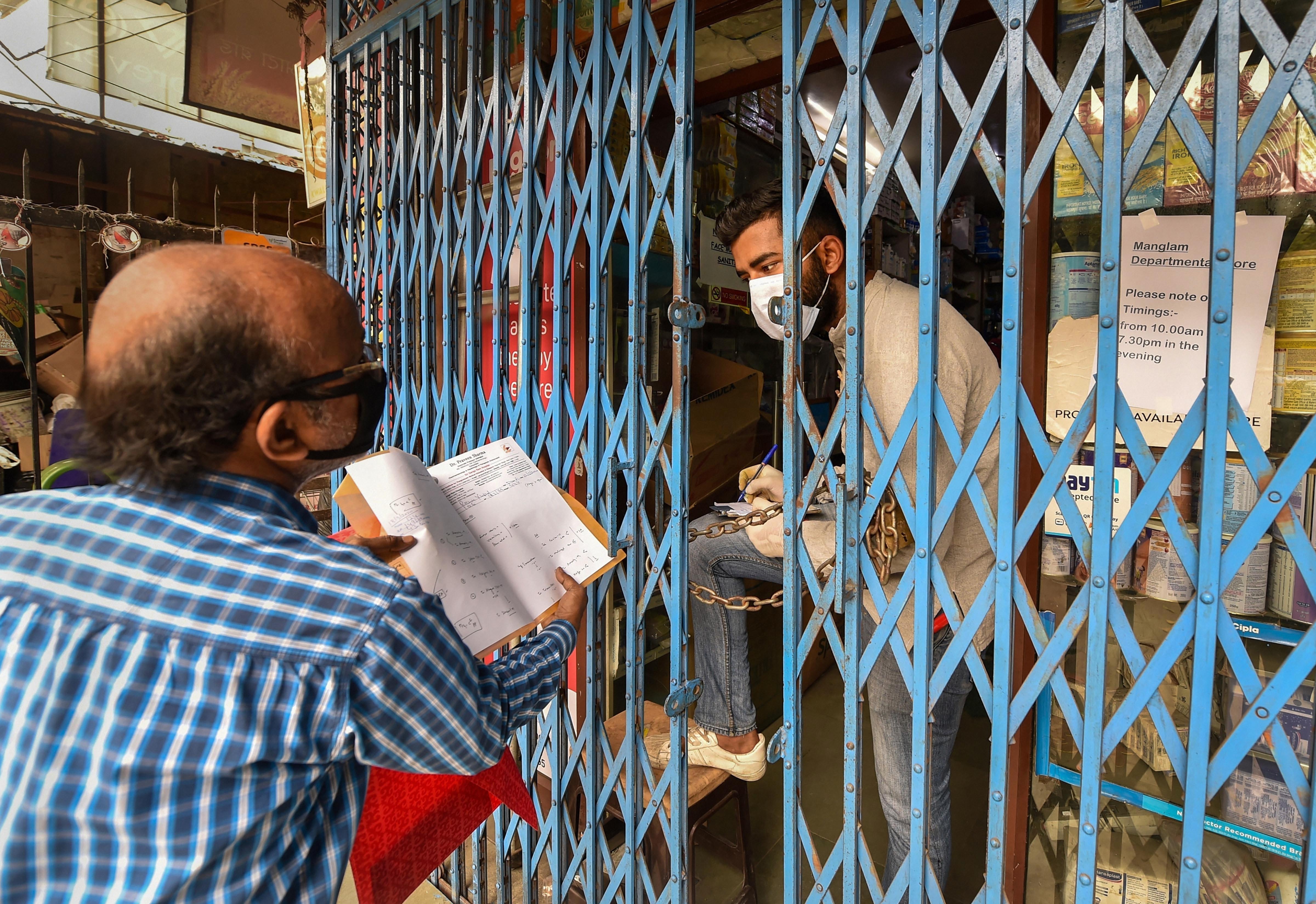 An employee takes protection while giving medicines to customers, during the nationwide complete lockdown in view of the coronavirus pandemic, in New Delhi, Thursday, March 26, 2020
