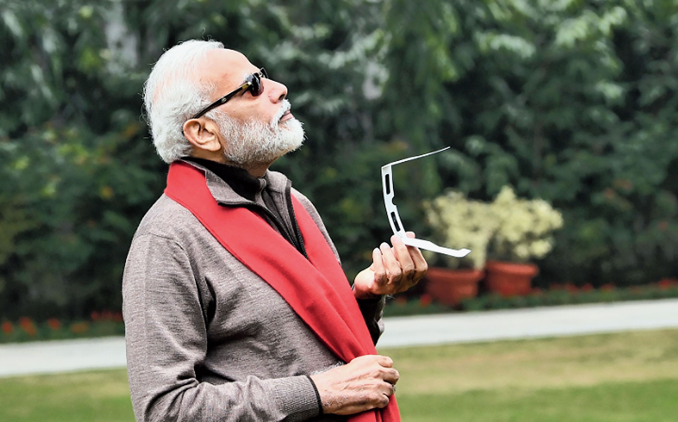 Prime Minister Narendra Modi looks at the sky to catch a glimpse of the annular solar eclipse in New Delhi on Thursday.