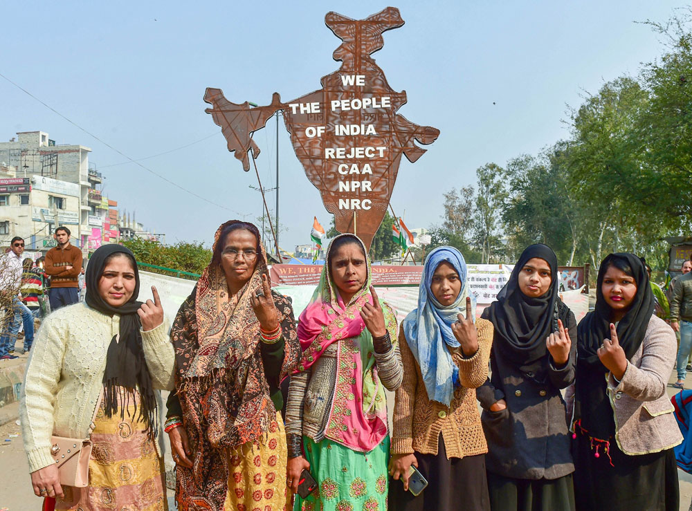 Protesters show their ink-marked fingers after casting votes for the Delhi Assembly elections, near the site of their peaceful agitation against the Citizenship Act, in Shaheen Bagh, New Delhi, on Saturday