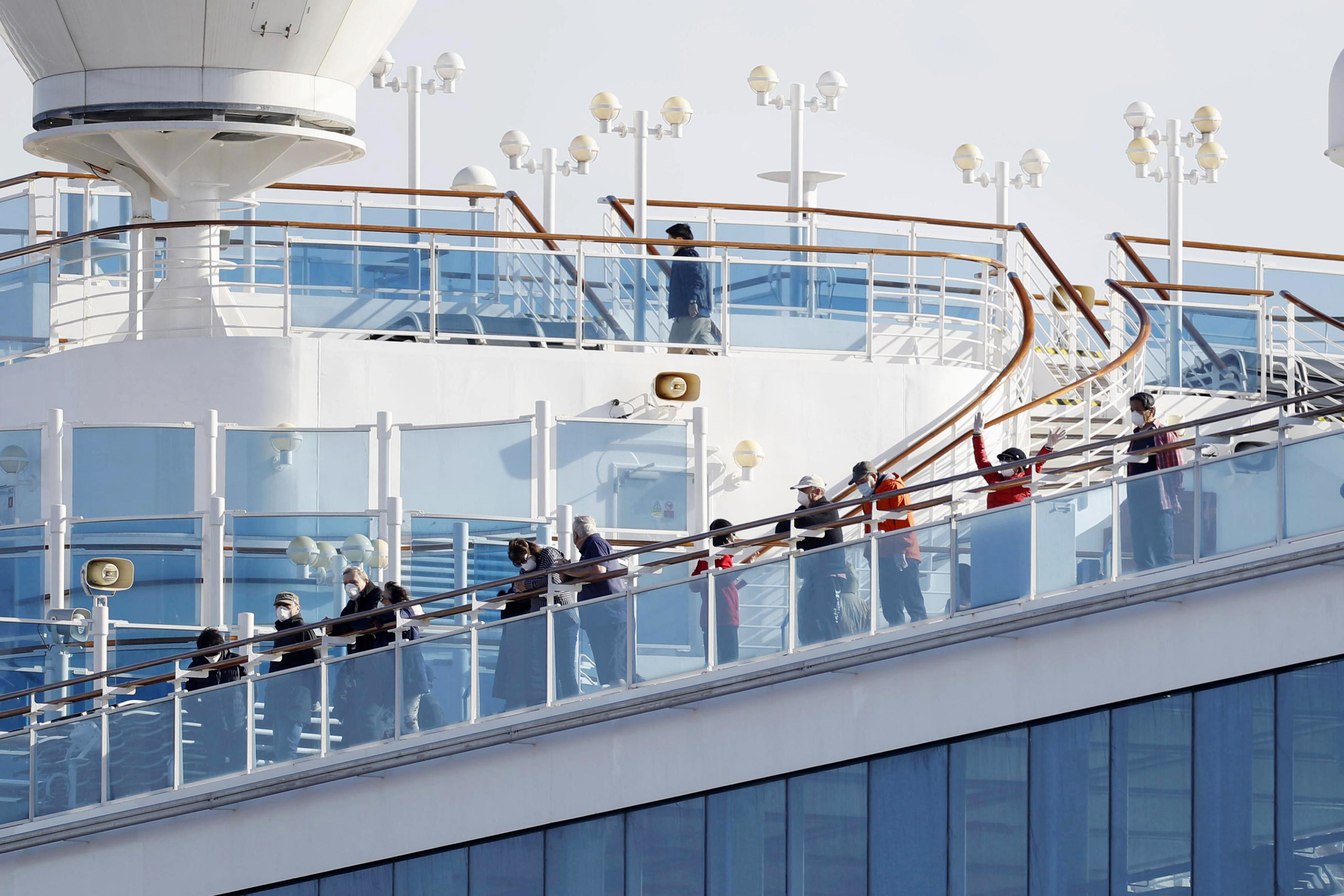 Passengers stand on the deck of the Diamond Princess cruise ship anchored at Yokohama Port in Yokohama, near Tokyo on Wednesday