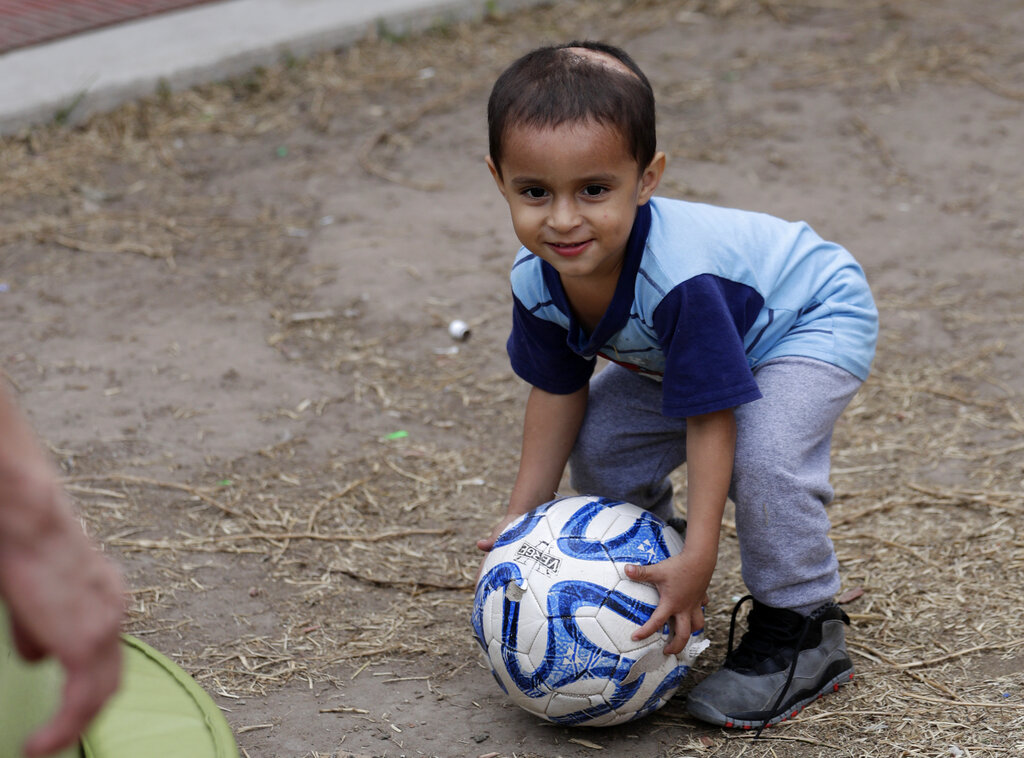 Maria Orbelina Cortez's 3-year-old son, Julio, plays with a soccer ball at the Catholic Charities shelter in McAllen, Texas. Orbelina says she decided to flee El Salvador after her husband attacked her and caused a pan of hot oil to fall, scalding the child and leaving a scar on his head.
