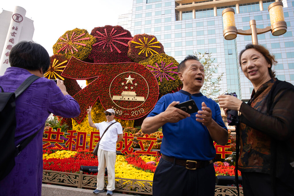 Residents pose for photos near a floral decoration in Beijing on Saturday