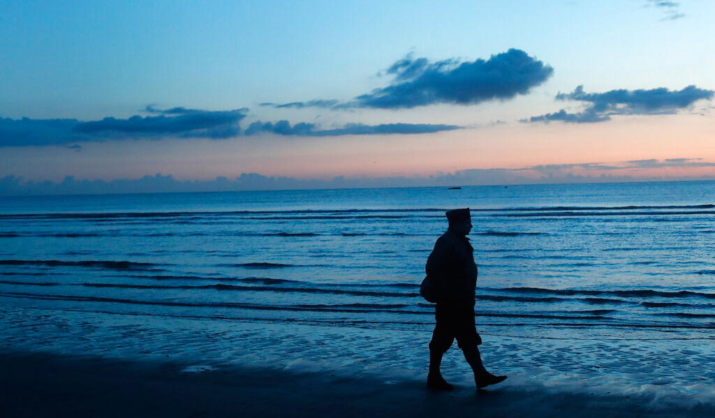 A World War II re-enactor stands on Omaha Beach, in Normandy, France, at dawn on Thursday, June 6, 2019 during commemorations of the 75th anniversary of D-Day.