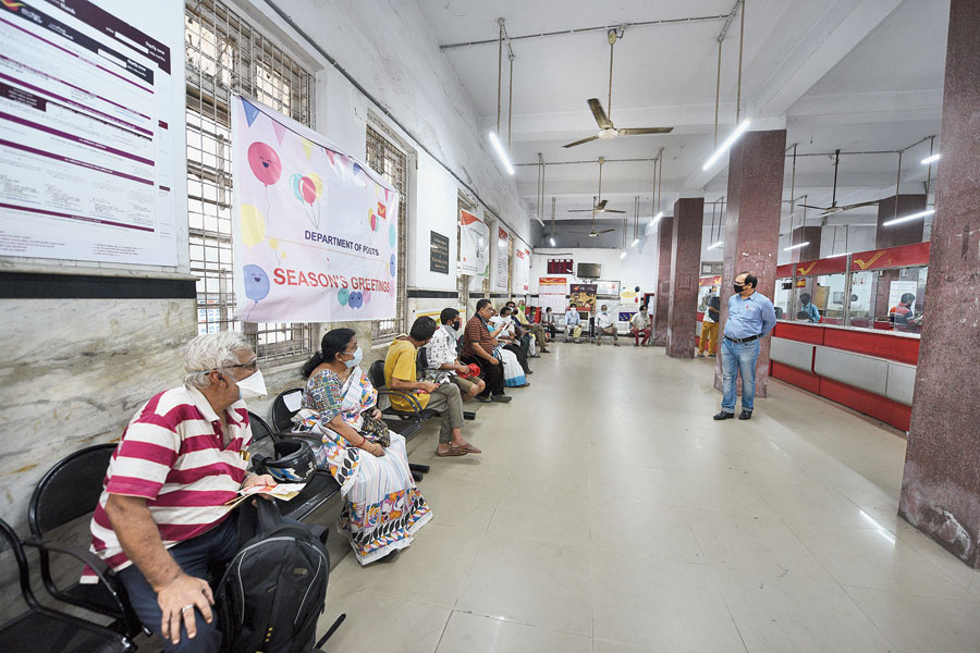 Pensioners and others maintain social distancing as they wait inside Tollygunge head post office on Friday morning.