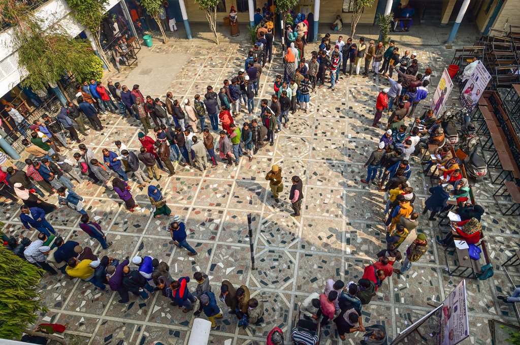 People wait in queues to cast their votes at Shaheen Public School polling station in the Shaheen Bagh area, which has been witnessing a peaceful protest against the Citizenship Act for several weeks, during the Delhi Assembly elections, in New Delhi, on Saturday