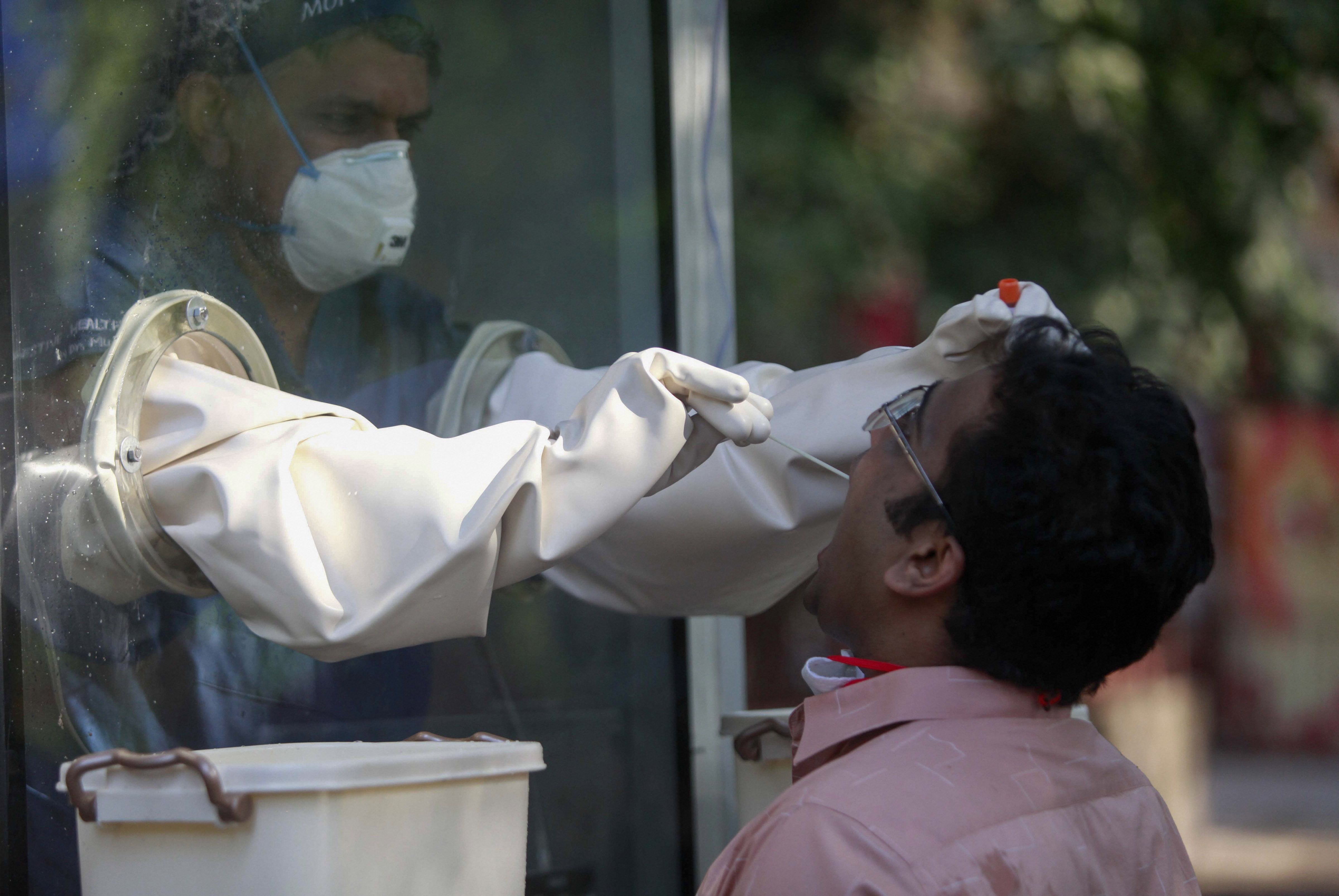 A medic collects swab sample of a man from a new swab testing cabin at Podar hospital in Worli during a nationwide lockdown in the wake of coronavirus pandemic, in Mumbai, Saturday, April 18, 2020.