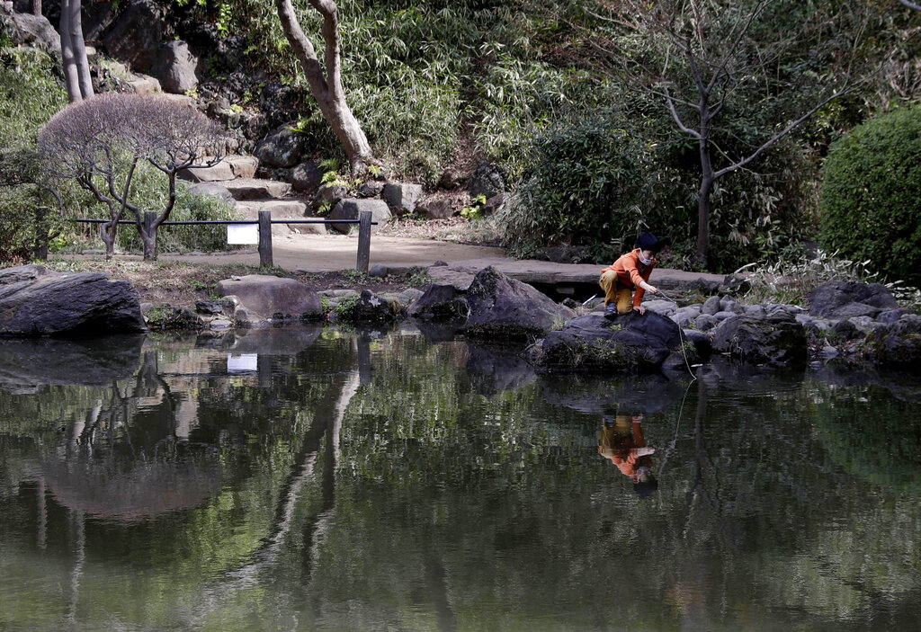 A child casts his makeshift fishing line into the lake of the Arisugawa-no-miya Memorial Park in Tokyo, Monday